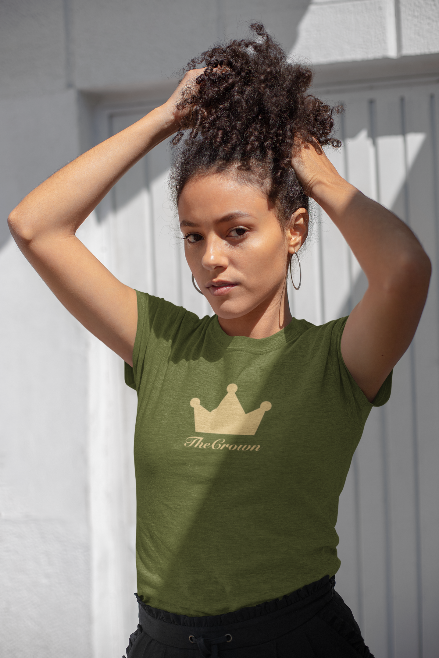 Beautiful woman wearing olive-green tee with the crown design across chest